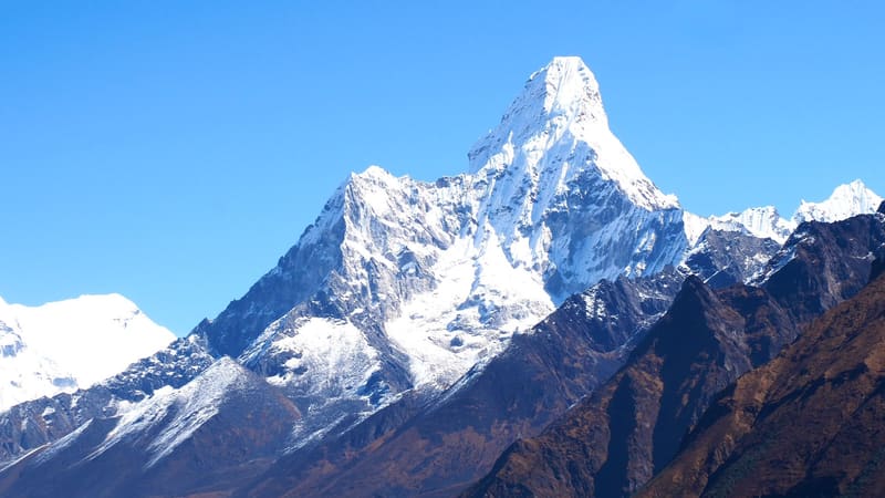 The snow-covered pyramid of Ama Dablam against a clear blue sky