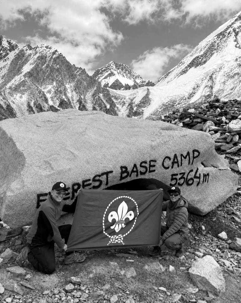 Black-and-white photo of David and Furi Sherpa holding a Scout flag at the Everest Base Camp rock